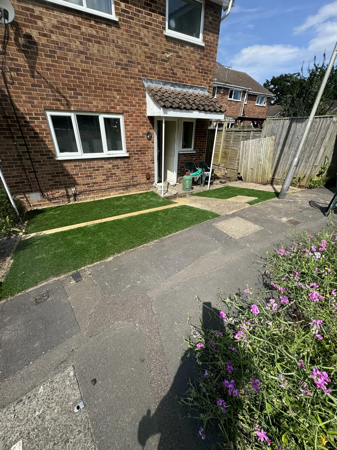 Artificial lawn and slab path at the front of a brick semi-detached house