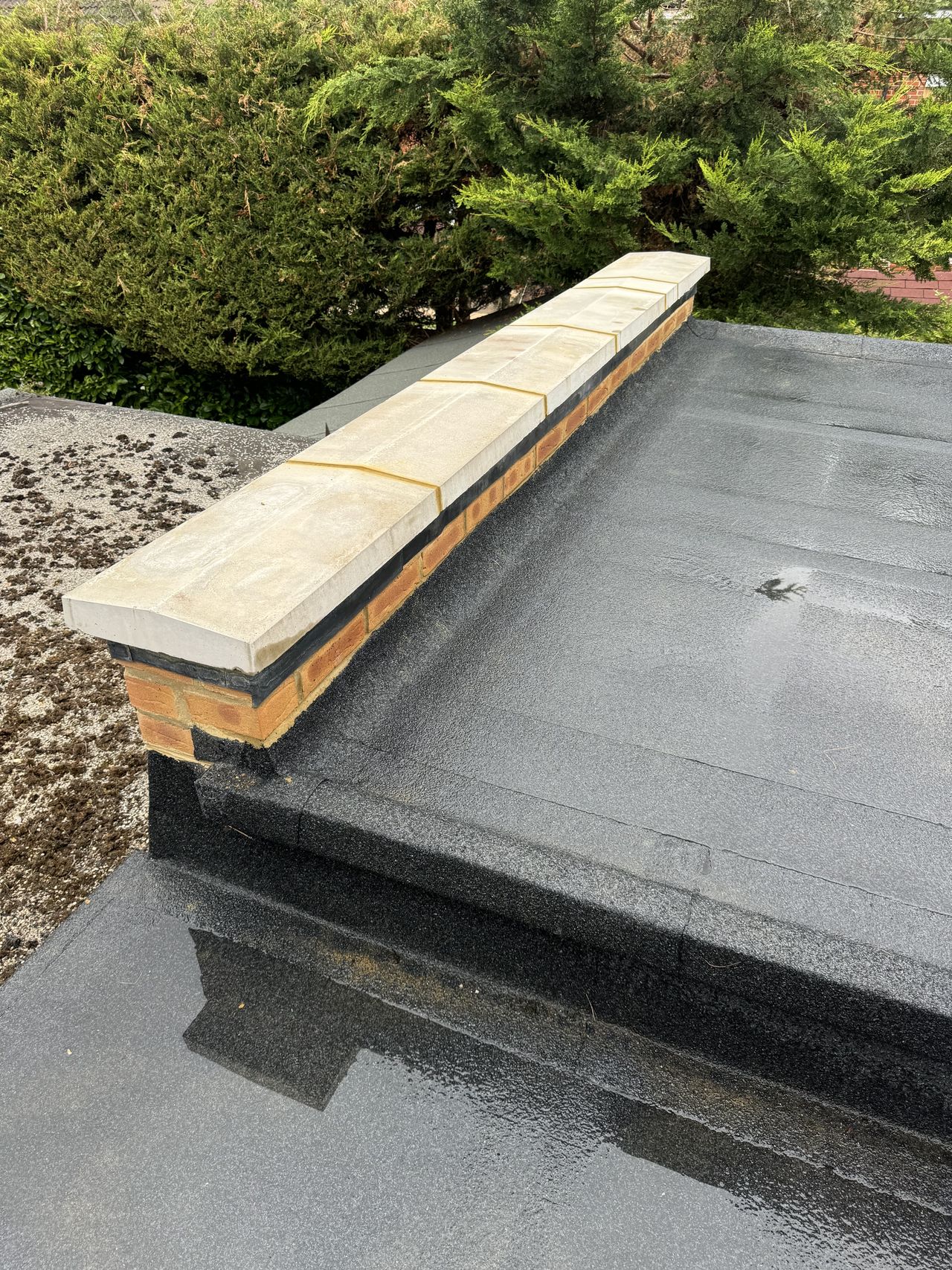 Flat roof with new stone coping bedded on a parapet wall