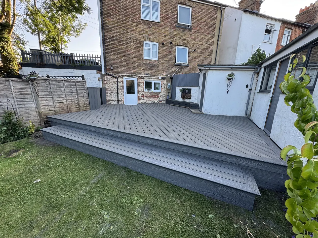 Grey composite decking platform across the back garden of a three-storey house