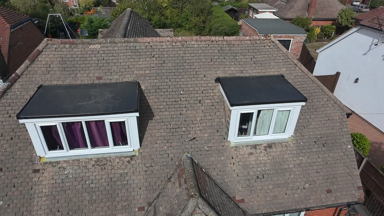Two dormer windows on a tiled roof, each with a new flat roof and white fascia, seen from above