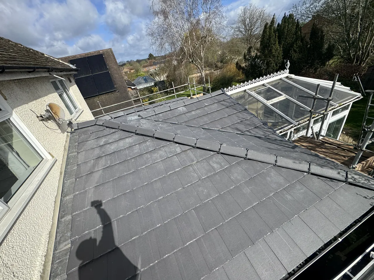 Grey tiled extension roof beside a neighbour's old glass conservatory