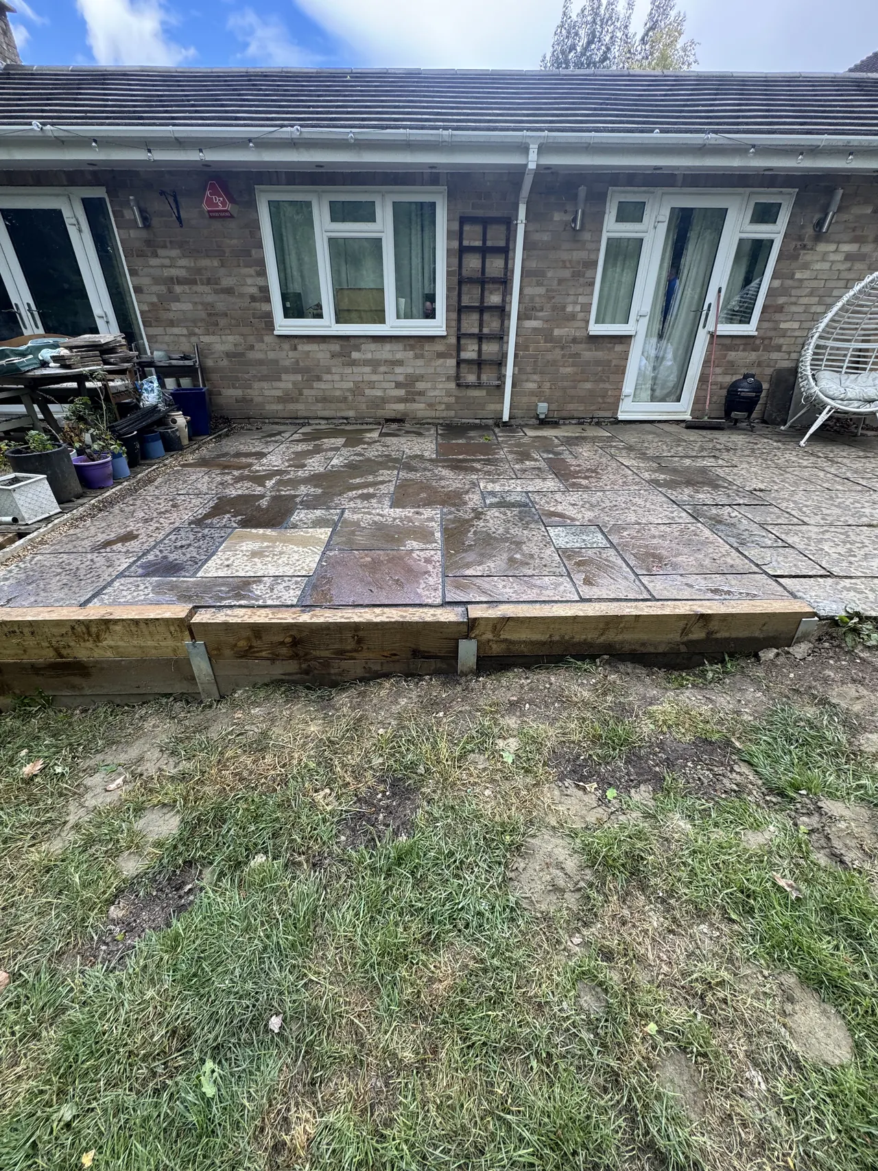 New slab patio raised on timber sleepers at the back of a brick bungalow